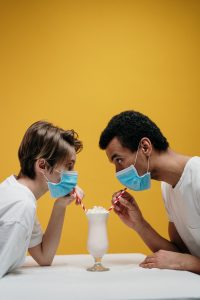 Two people wearing mask sharing a drink